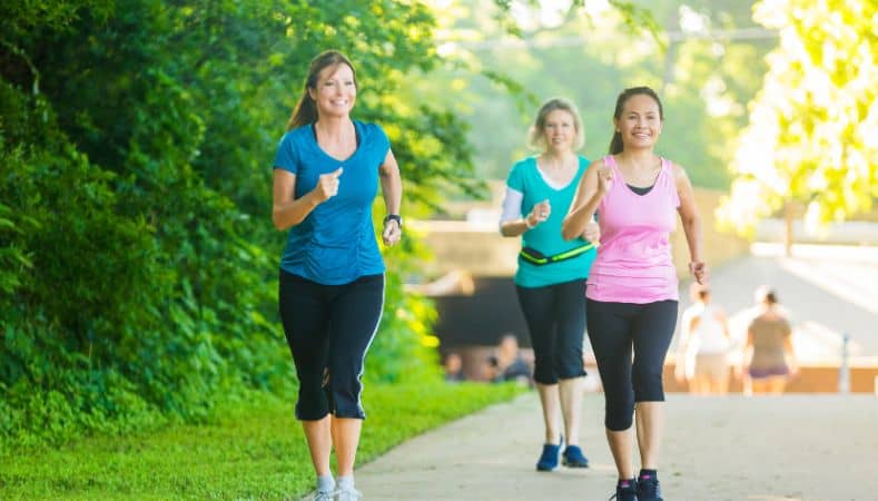 Tres personas practicando power walking por zona verde urbana