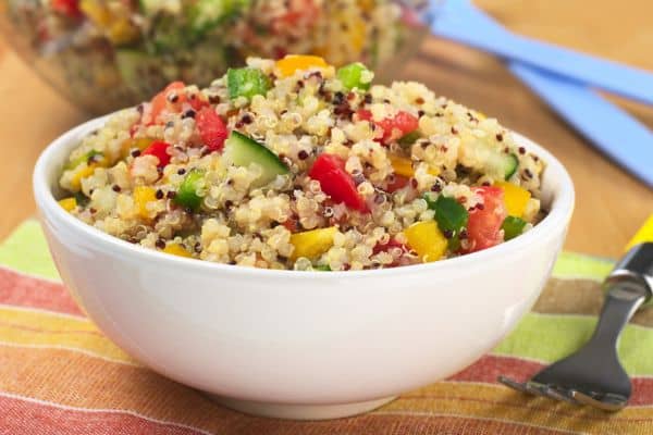 Bol de ensalada de quinoa con verduras como pimiento rojo, verde y amarillo y calabacín