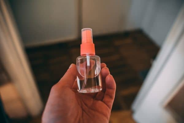 Sujetando con la mano un recipiente de con pulverizador similar a la Cristalmina