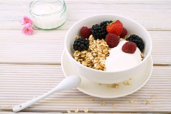 Desayuno nutritivo con avena, yogurt sin azúcar y frutos silvestres variados