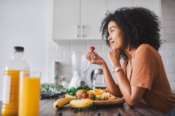 Mujer comiendo fruta antes del cepillado dental