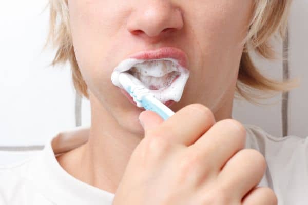 Persona cepillándose con espuma para eliminar placa bacteriana y 