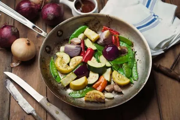 Sartén de acero sin antiadherente salteando verduras varias